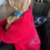 Person wearing a red hoodie with a blue scrunchie in their hair, sitting on a couch.